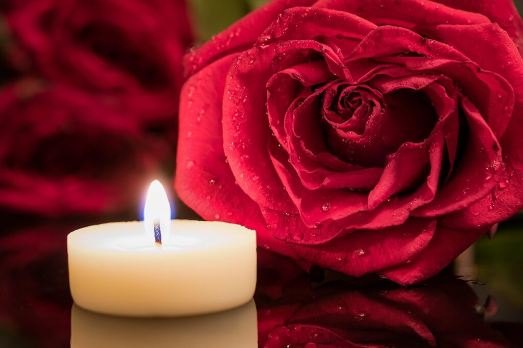 Vela encendida junto a una rosa roja para un ritual de pasión en pareja