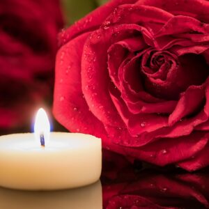 Vela encendida junto a una rosa roja para un ritual de pasión en pareja