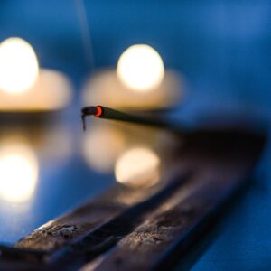 Vela encendida junto a varitas de incienso para un ritual en el hogar