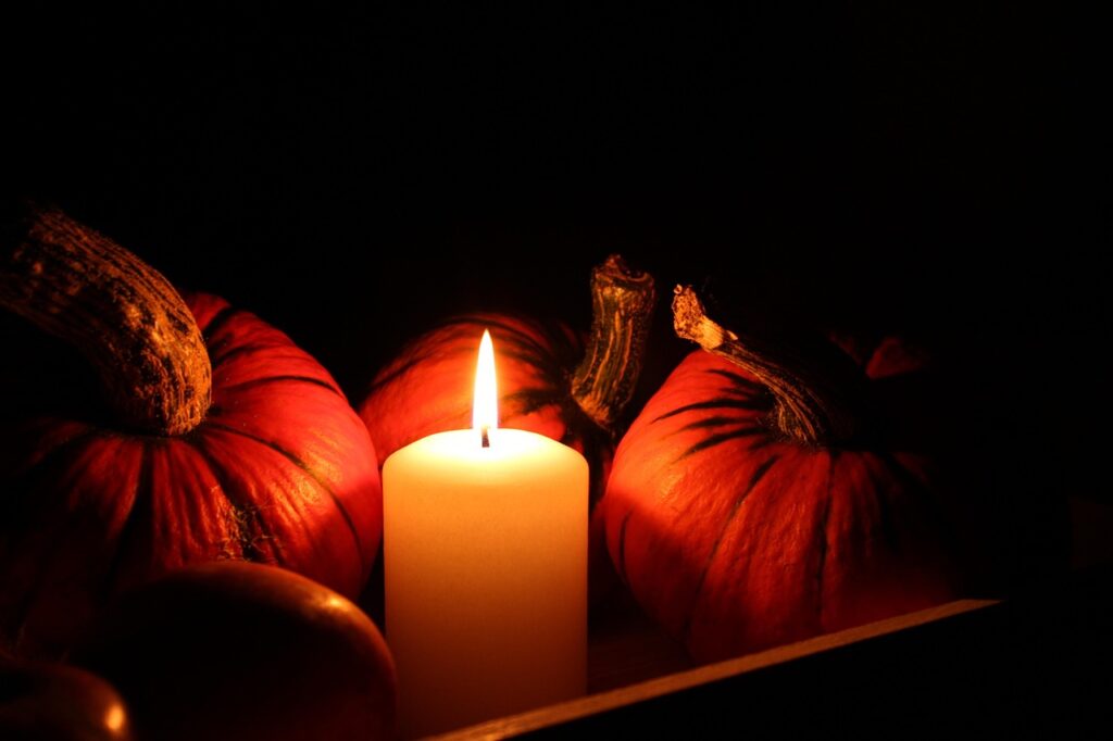 Calabaza de otoño junto a una vela encendida en un ambiente oscuro de Halloween