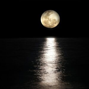 Luna llena reflejada sobre el mar en un cielo nocturno