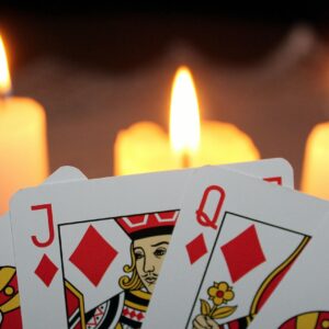 Vela encendida junto a cartas del tarot en la oscuridad