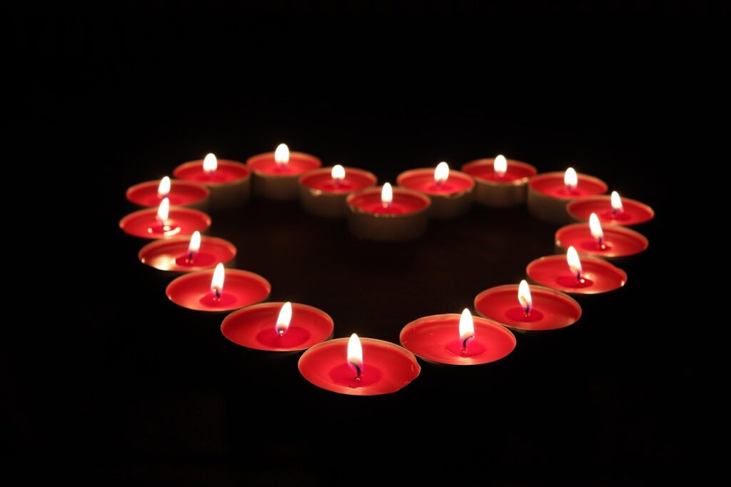 Vela encendida junto a un corazón rojo para un ritual de amor con foto