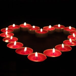 Vela encendida junto a un corazón rojo para un ritual de amor con foto