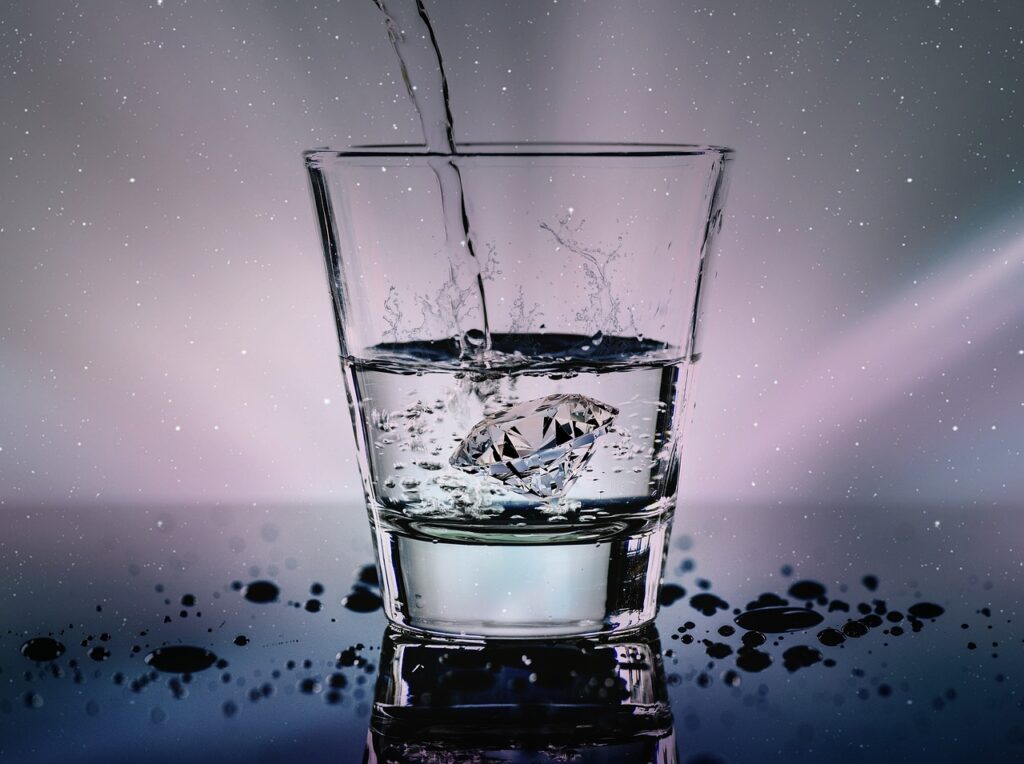 Vaso de agua cristalina iluminado, usado para preparar agua de luna llena
