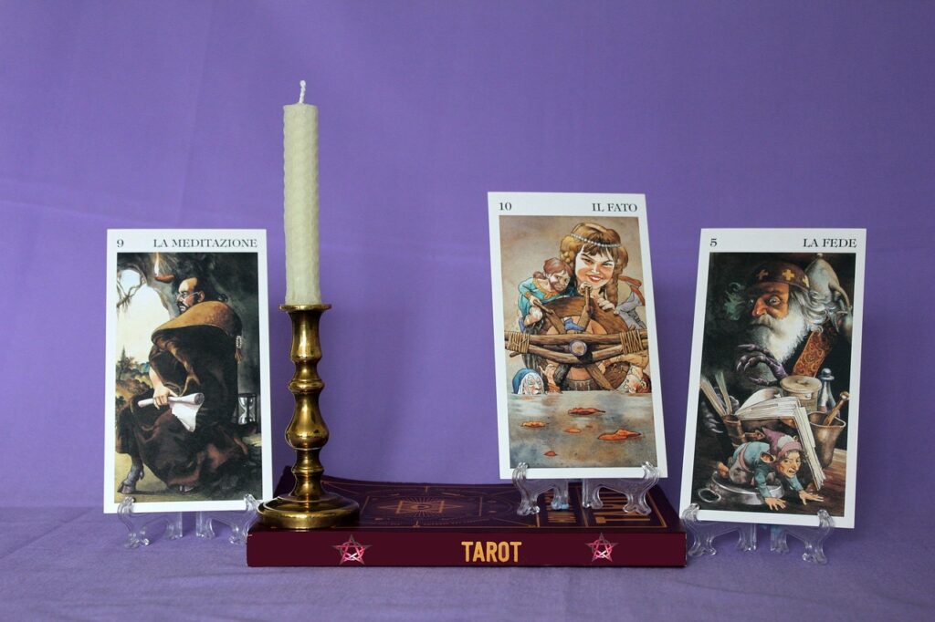 Cartas de tarot, un libro y una vela preparados para una consulta