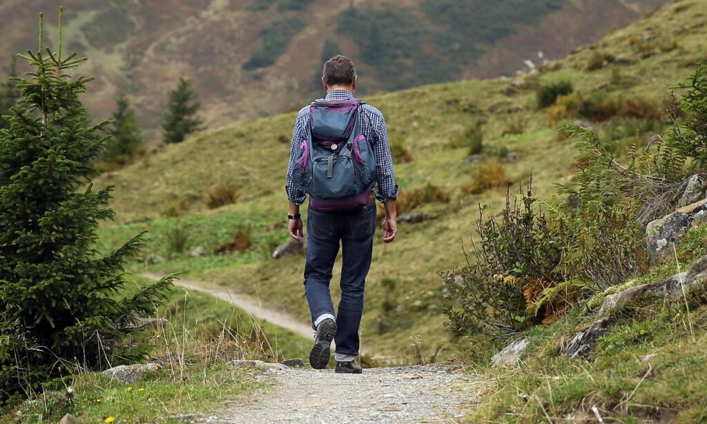Excursionista con mochila caminando por un sendero de montaña