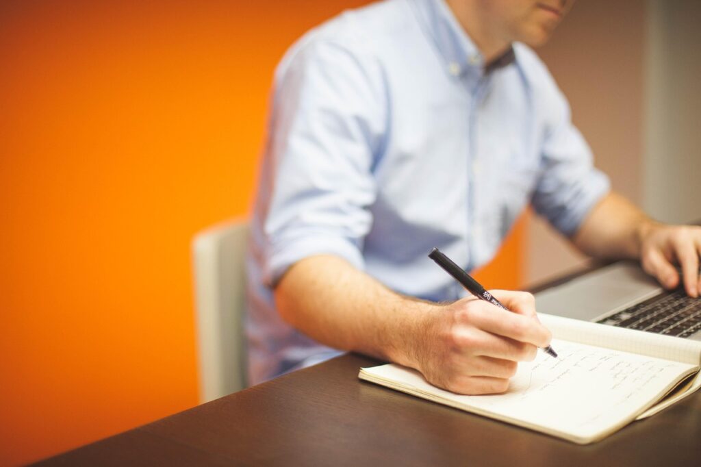 Persona escribiendo en una libreta sus decretos de abundancia