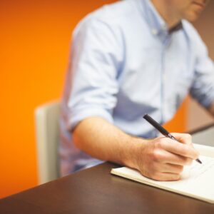 Persona escribiendo en una libreta sus decretos de abundancia