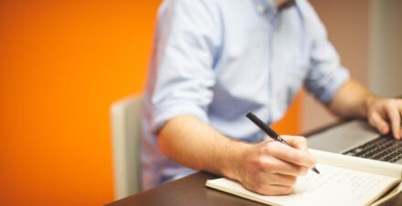 Persona escribiendo en una libreta sus decretos de abundancia