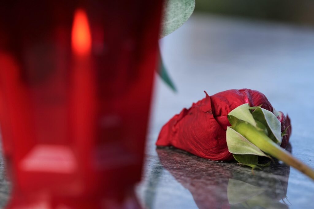 Vela encendida junto a una rosa roja y pétalos, símbolos de un ritual de amor en casa