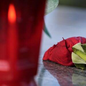 Vela encendida junto a una rosa roja y pétalos, símbolos de un ritual de amor en casa