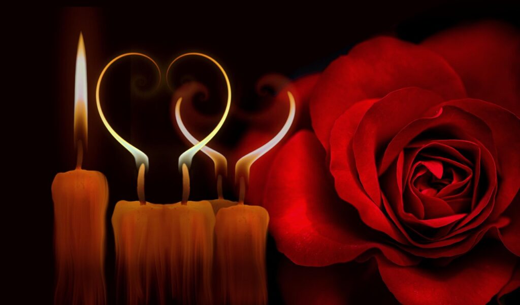 Vela encendida junto a una rosa roja y un corazón