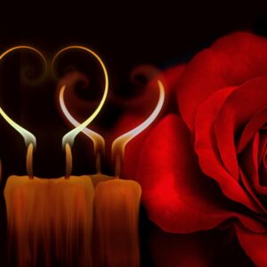 Vela encendida junto a una rosa roja y un corazón