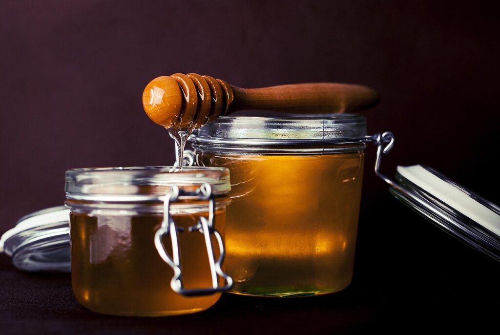 Frasco de miel con cuchara, símbolo del endulzamiento
